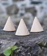Three Grapat natural wooden cones placed on a stone wall. 