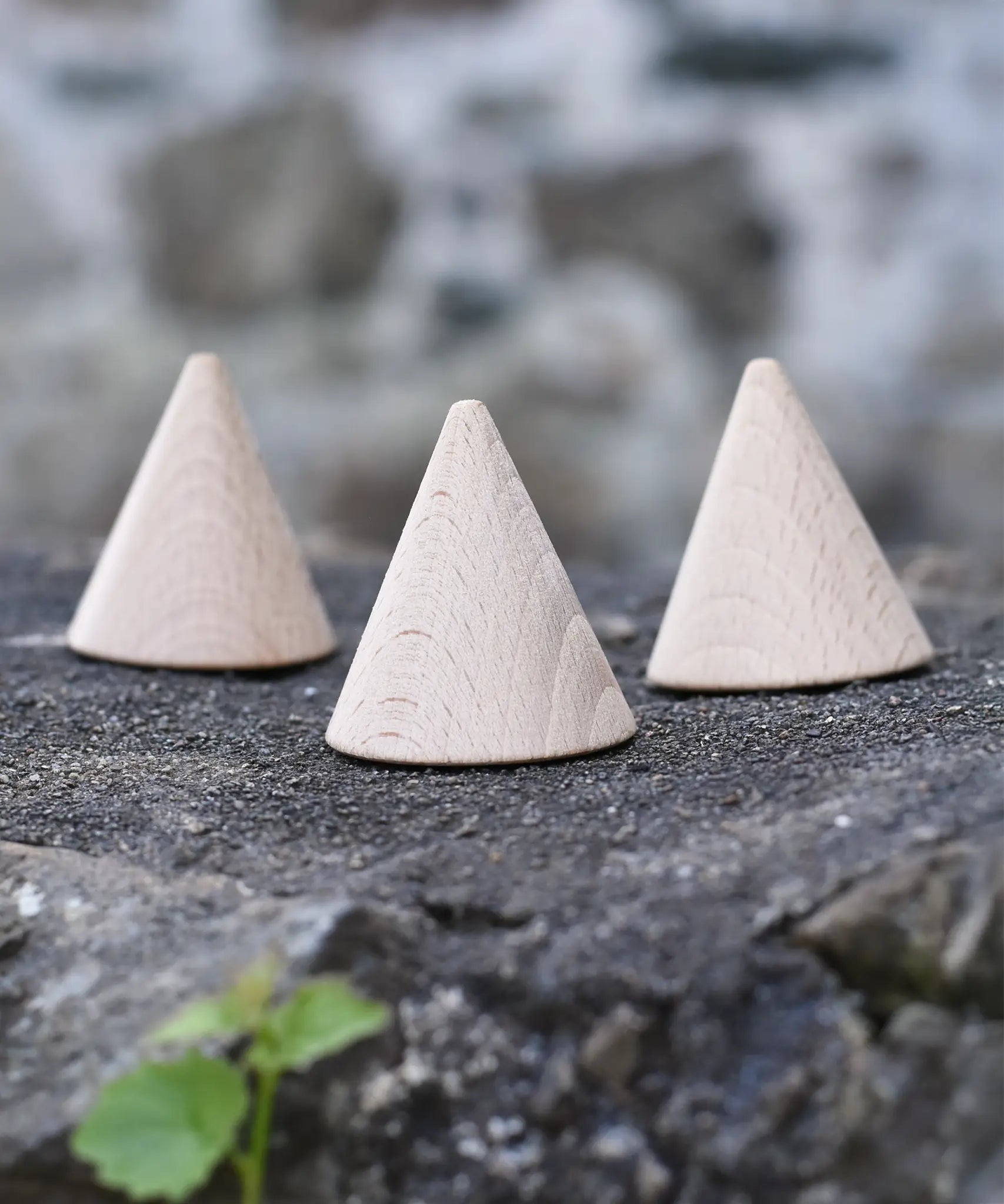 Three Grapat natural wooden cones placed on a stone wall. 