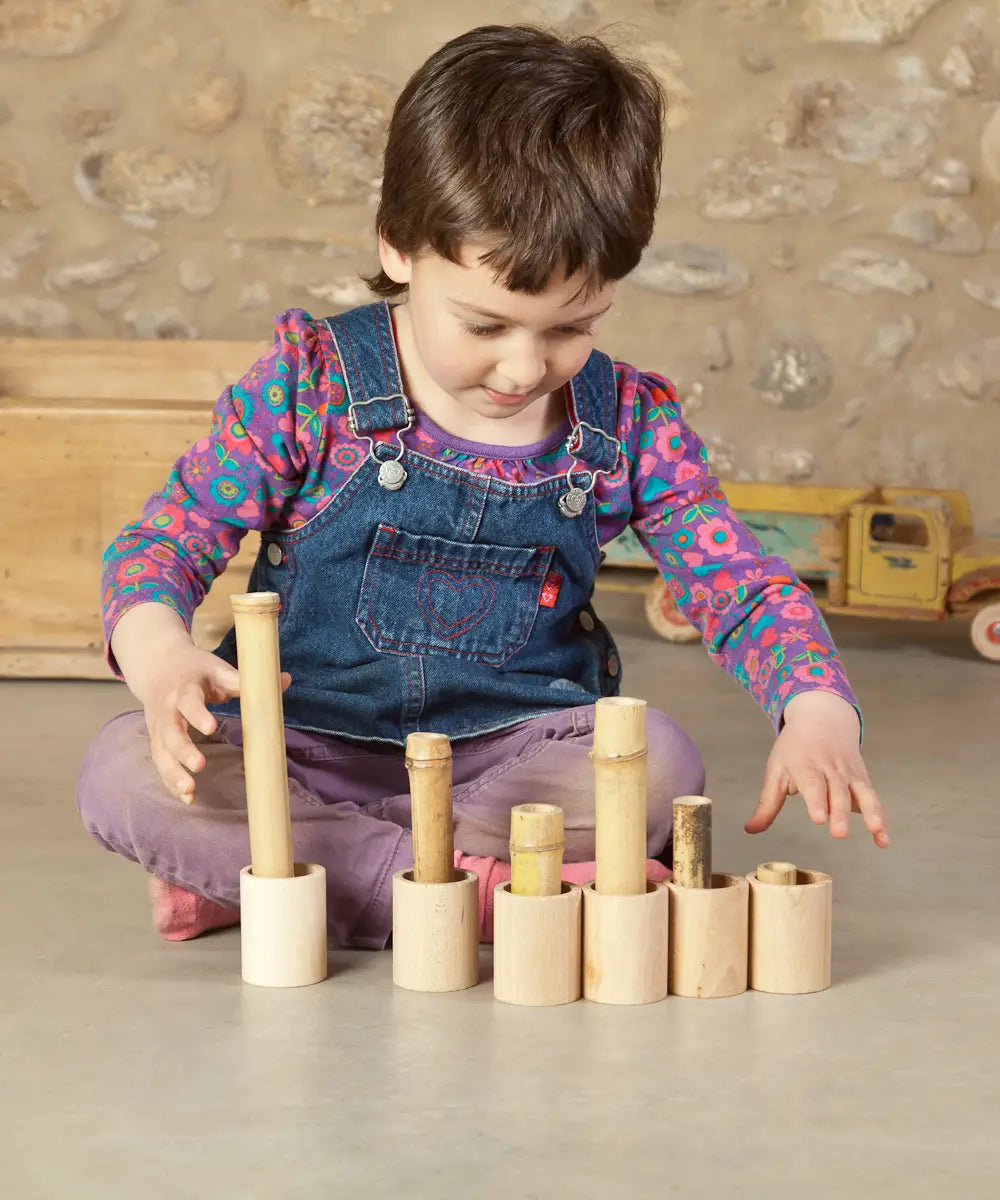Child sorting bamboo sticks in the Grapat handcrafted unpainted wooden cups with matching lids