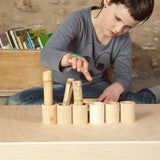 Row of Grapat handcrafted unpainted wooden cups with a bamboo sticks inside and a child in the background.