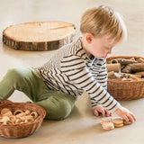 Child sorting Grapat's natural handcrafted wooden disks on a concrete floor