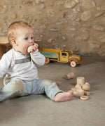 Child holding a Grapat handcrafted wooden half sphere loose pieces on a concrete surface