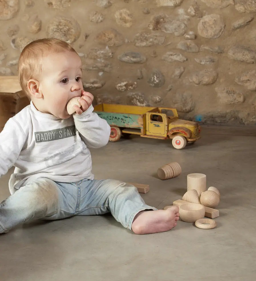Child holding a Grapat handcrafted wooden half sphere loose pieces on a concrete surface