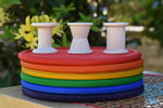 Grapat loose parts 3 natural wooden spools stacked on a stack of Grapat rainbow dishes.