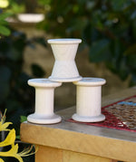 Grapat loose parts 3 natural wooden spools stacked on a stool. 