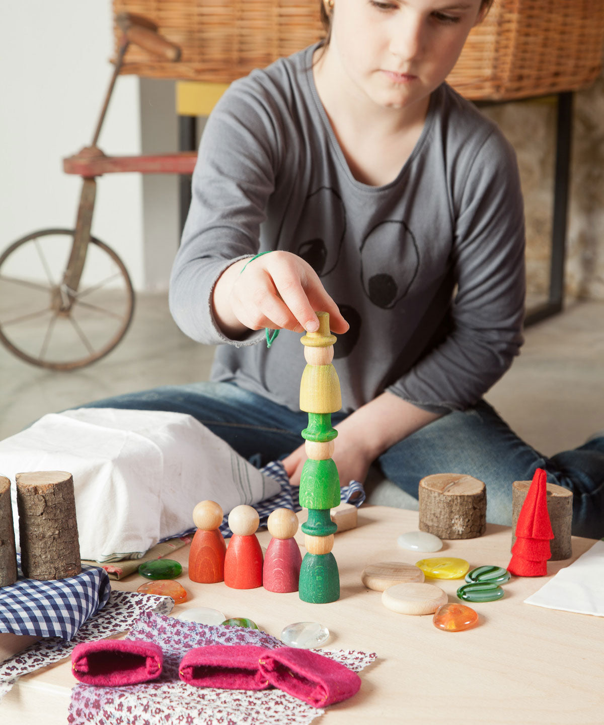 A child stacking Nins from the Grapat Nins® Of The Forest Peg Doll Play Set. These wooden toys are part of a wide range of open ended toys available at Babipur.  