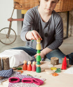 A child stacking Nins from the Grapat Nins® Of The Forest Peg Doll Play Set. These wooden toys are part of a wide range of open ended toys available at Babipur.  