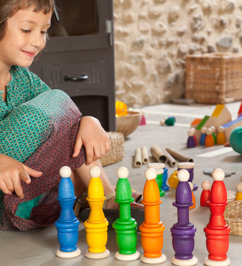 A child playing with the Grapat Wooden Peg Doll Nins®, Mates (Cups) and Coins in 6 rainbow colours. These wooden toys are part of a wide range of open ended toys available at Babipur.  