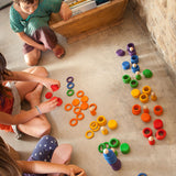 Children playing with the Grapat Wooden Peg Doll Nins®, Rings and Coins wooden toy play set. These wooden toys are part of a wide range of open ended toys available at Babipur.  