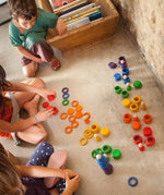 Children playing with the Grapat Wooden Peg Doll Nins®, Rings and Coins wooden toy play set. These wooden toys are part of a wide range of open ended toys available at Babipur.  