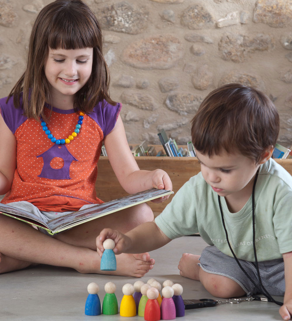A child playing with the Grapat 12 Rainbow Nins wooden peg dolls. These wooden toys are part of a wide range of open ended toys available at Babipur.  