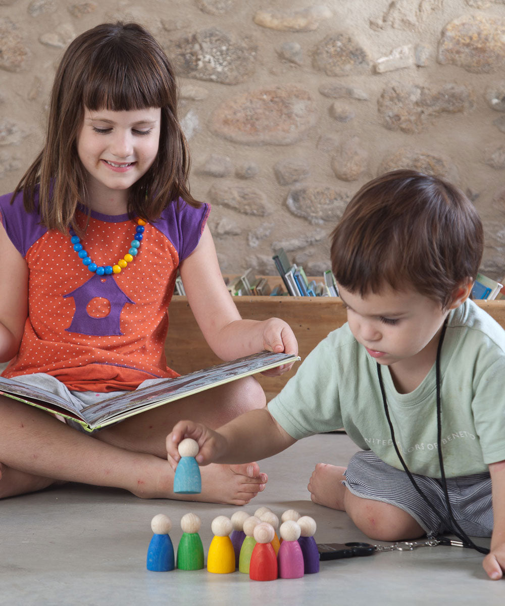 A child playing with the Grapat 12 Rainbow Nins wooden peg dolls. These wooden toys are part of a wide range of open ended toys available at Babipur.  