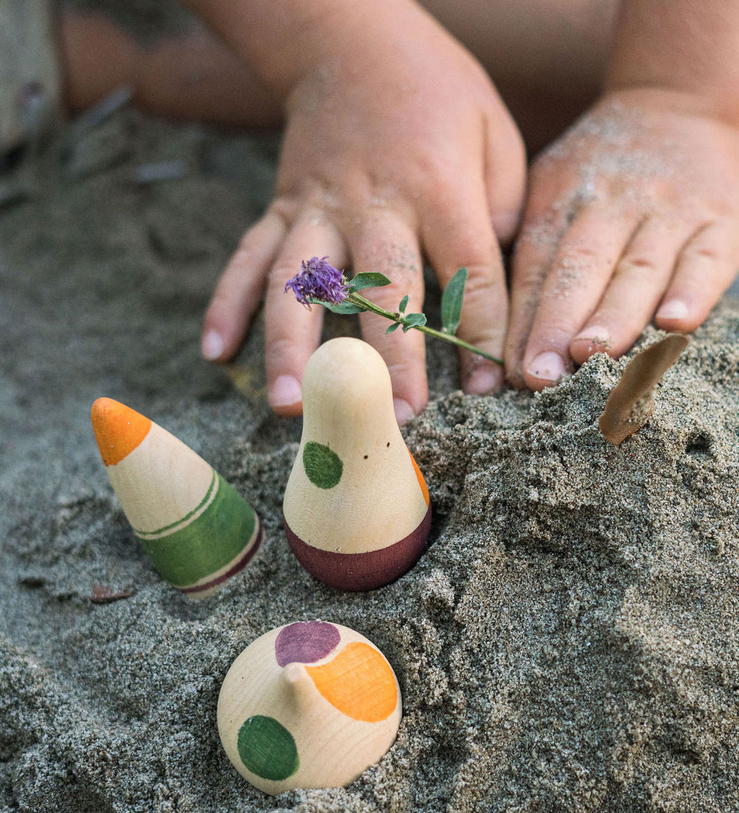 A close up of a child's hands next to Grapat Ooh-Lala! Set placed in snad. 