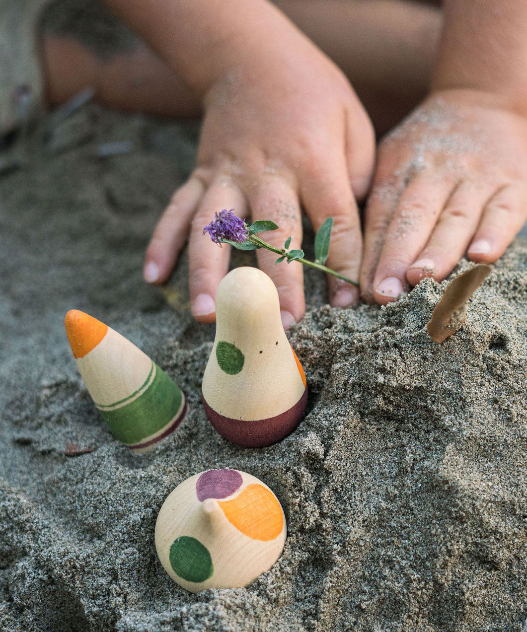 A close up of a child's hands next to Grapat Ooh-Lala! Set placed in snad. 