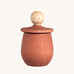 Grapat orange Little Things. A wooden top with eyes drawn on and an orange coloured pot to match. Grapat have a wide range of wooden toys and loose parts available at Babipur. 