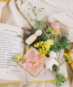 The pieces from the Grapat and Ostheimer collaboration  Handmade Seasonal Play Set Hello Spring Set laid out on a book with flowers.