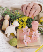 A child hand reaching in to play with the pieces from the Grapat and Ostheimer collaboration  Handmade Seasonal Play Set Hello Spring.