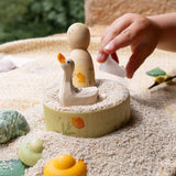 The small wooden bowl from the Grapat / Ostheimer Hello Summer set filled with sand with the peg doll and goose sitting inside. 