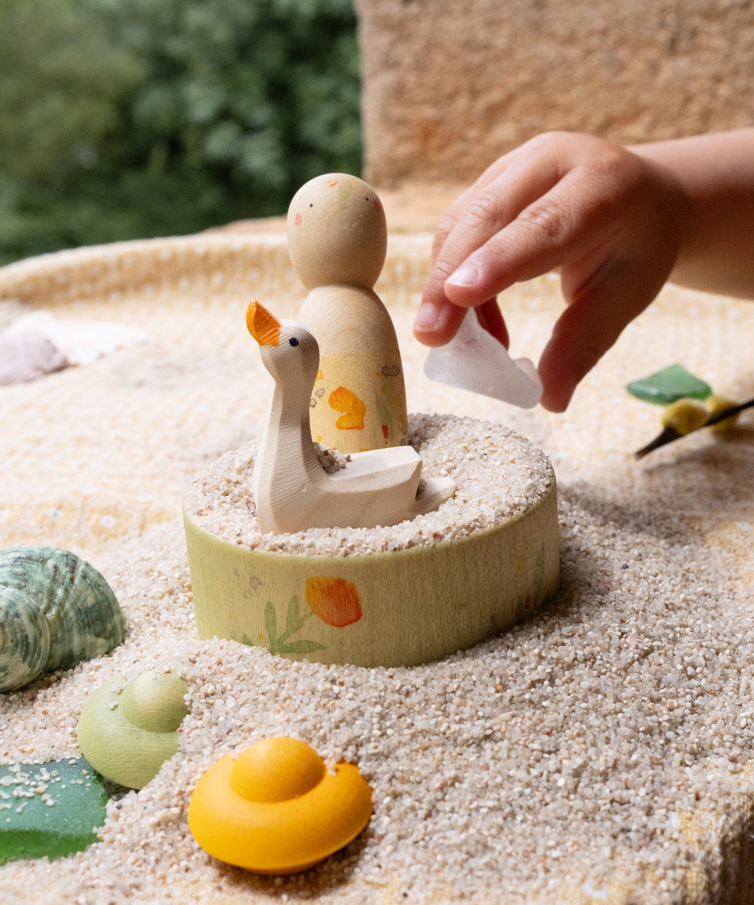 The small wooden bowl from the Grapat / Ostheimer Hello Summer set filled with sand with the peg doll and goose sitting inside. 