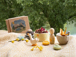 A decorative display outside with the Grapat / Ostheimer Hello Summer wooden figures on  a table cloth. Features a goose, peg doll, bowl and 2 mandala pieces. 