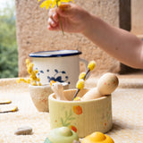 A close up of the Grapat / Ostheimer Hello Summer set showing the wooden goose and peg doll sitting inside the small doll with the 2 mandala pieces in front. Showing a child's hand holding a flower in background. 