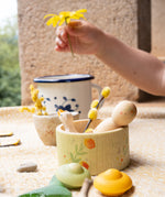 A close up of the Grapat / Ostheimer Hello Summer set showing the wooden goose and peg doll sitting inside the small doll with the 2 mandala pieces in front. Showing a child's hand holding a flower in background. 