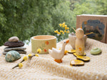 A decorative outdoor display with the Grapat / Ostheimer Hello Summer wooden figure set on a table cloth showing the hand painted detail with the decorative cardboard box in the background.