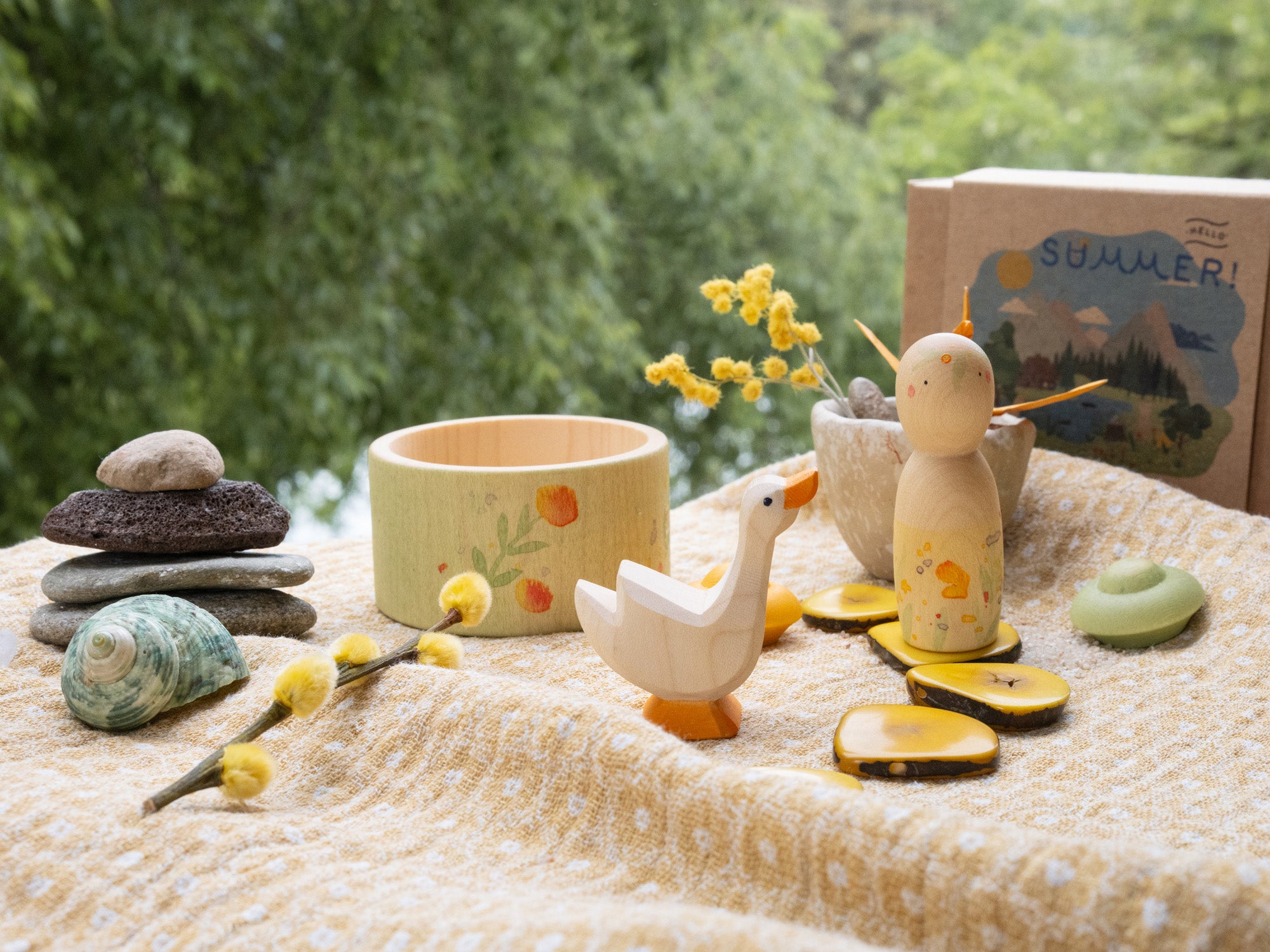 A decorative outdoor display with the Grapat / Ostheimer Hello Summer wooden figure set on a table cloth showing the hand painted detail with the decorative cardboard box in the background.