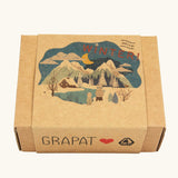 The box that the The Grapat Ostheimer Limited Edition Hello Winter wooden toy set comes in available at Babipur. Features 5 hand cut and hand painted figures and pieces including a peg doll, small decorative bowl, owl and 2 green coloured snowdrop mandala pieces. 