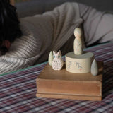 The Grapat Ostheimer Limited Edition Hello Winter wooden toy set available at Babipur. Features 5 hand cut and hand painted figures and pieces including a peg doll, small decorative bowl, owl and 2 green coloured snowdrop mandala pieces. The set has been placed on a wooden box, a child can be seen laying in the background. 