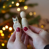 Grapat x Ostheimer Hello Winter limited edition wooden toy play set. An adult's hand is holding the Ostheimer owl and Grapat peg doll close to the camera. These limited edition sets are available here at Babipur. 