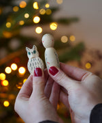 Grapat x Ostheimer Hello Winter limited edition wooden toy play set. An adult's hand is holding the Ostheimer owl and Grapat peg doll close to the camera. These limited edition sets are available here at Babipur. 