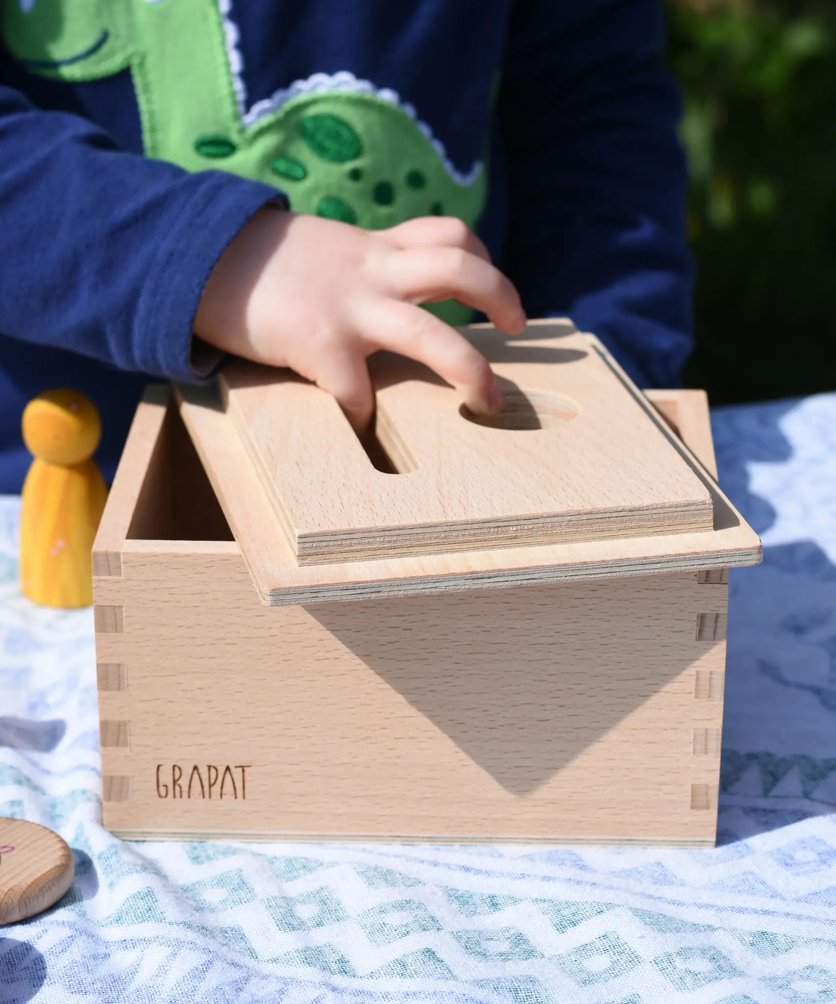 Child placing the lid upside down on the Grapat permanence box. 