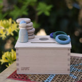 Grapat object permanence box with wooden coins, rings and Nins placed on the lid.