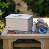 Grapat object permanence box placed on a stool with Nins, coins and rings placed besides it.