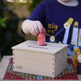 Child posting a Nin peg doll into the Grapat permanence box. 