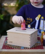 Child posting a Nin peg doll into the Grapat permanence box. 