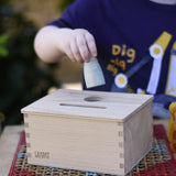Grapat object permanence box, child posting a blue animal Nins through the circular shaped hole.
