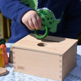 Child posting a green ring into the slot on the Grapat object permanence box. 