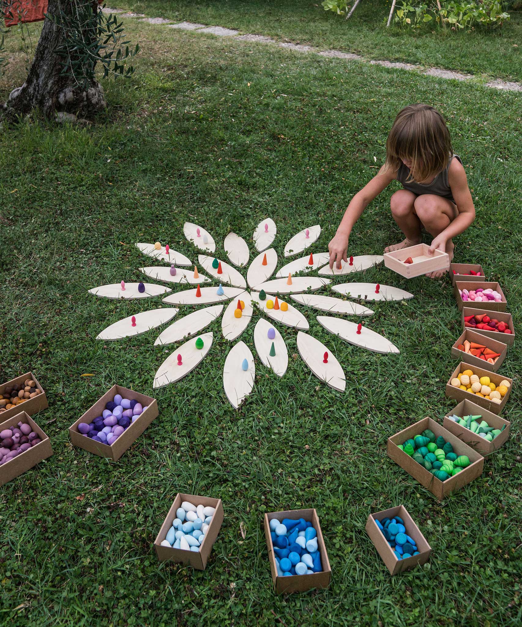 A child playing with the Grapat petals wooden platform.  A set of 24 wooden petals. These platform bases are perfect for use with Grapat mandala pieces. These wooden petals are part of a huge range of open ended wooden toys from Grapat available here at Babipur.
