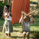 A child holding two of the Grapat petals wooden platforms above tjher head to look like bunny ears. These are a set of 24 wooden petals. These wooden petals are part of a huge range of open ended wooden toys from Grapat available here at Babipur.