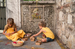Child weaving some string into the thread of the Grapat handmade weaving frame toy