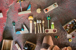 Close up of pieces from the Grapat happy place Waldorf toy set lined up of a stone floor