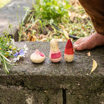 Close up of the Grapat yay wooden toy set on a stone wall next to a childs feet
