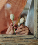 A close up of the Grapat wooden twin soul puppet. Showing  the light green flower pupper and grey mischievous girl with freckles puppet played with behind a window.