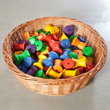 Grapat 36 Wooden Spools shown placed in a wicker basket. These wooden toys are part of a wide range of open ended toys available at Babipur.  