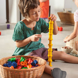 A child playing with the Grapat set of 36 wooden rainbow coloured spools, stacking the yellow spool on top of each other. These wooden toys are part of a wide range of open ended toys available at Babipur.  