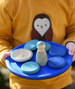 Blue Grapat rainbow dish in a child's hands with blue coloured toys placed on it. 