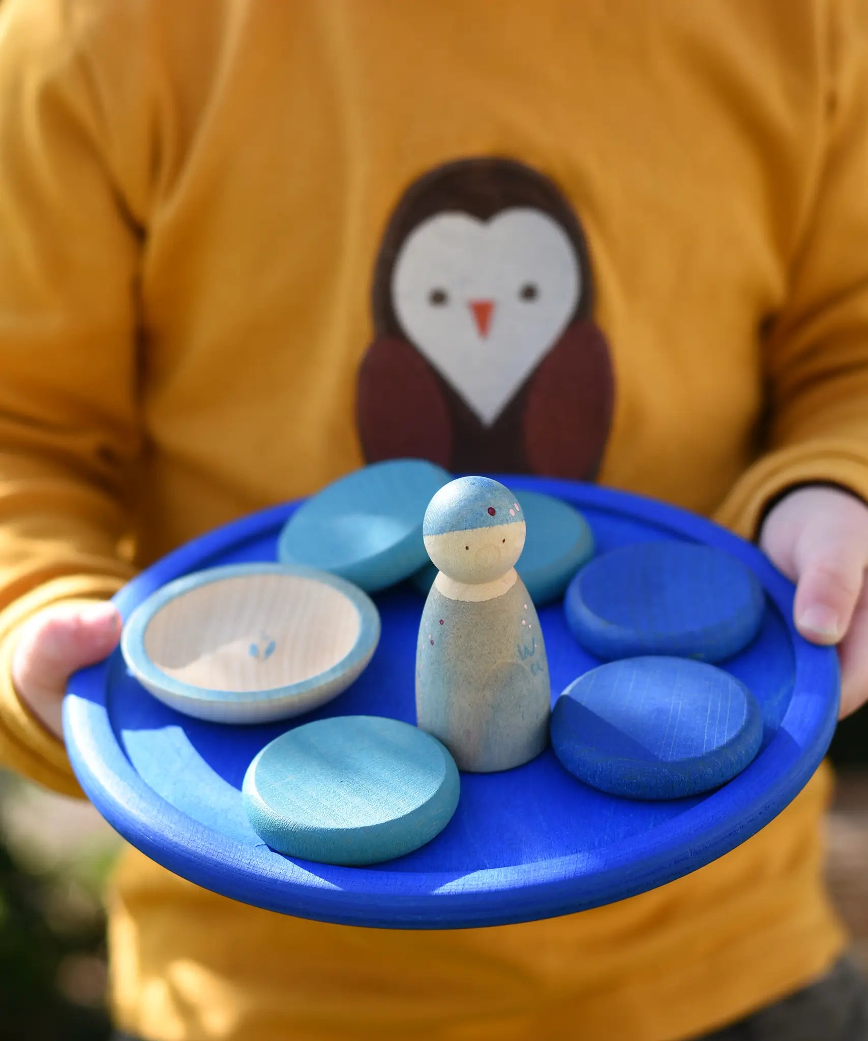 Blue Grapat rainbow dish in a child's hands with blue coloured toys placed on it. 