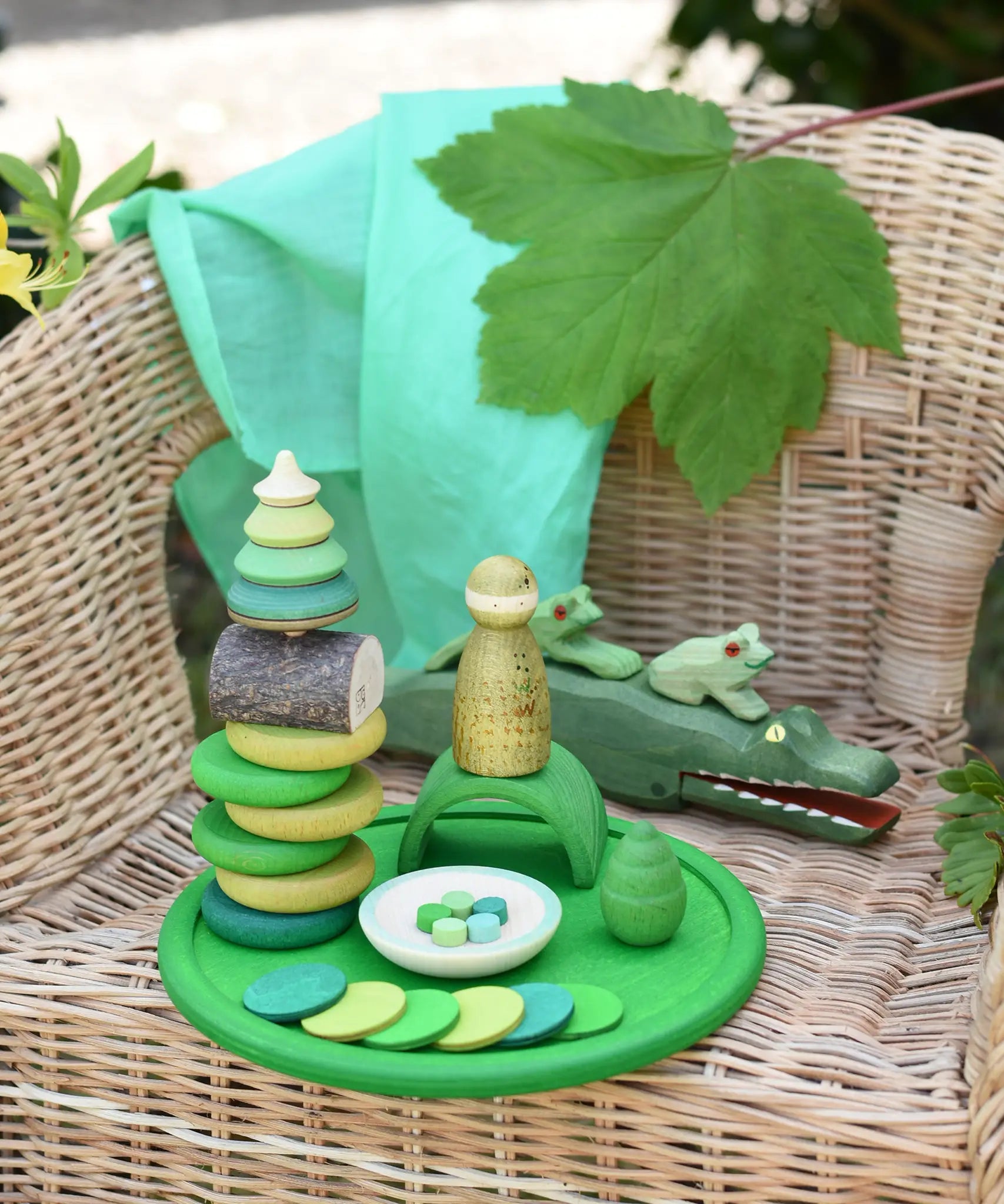 Green Grapat rainbow dish placed on a child's chair with green toys placed on it and on the chair. 